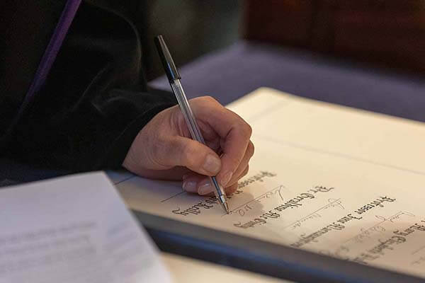 Person signing fellowship parchment