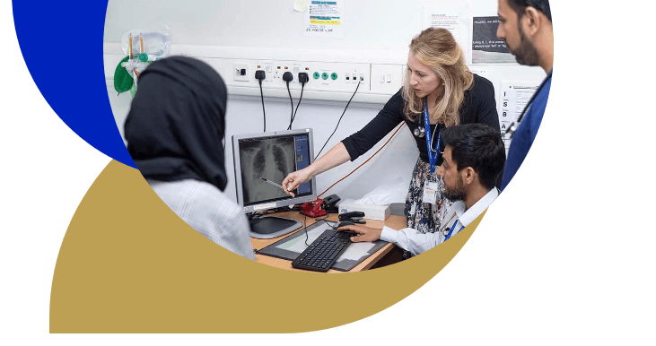 Female consultant points to computer screen surrounded by three medical trainees