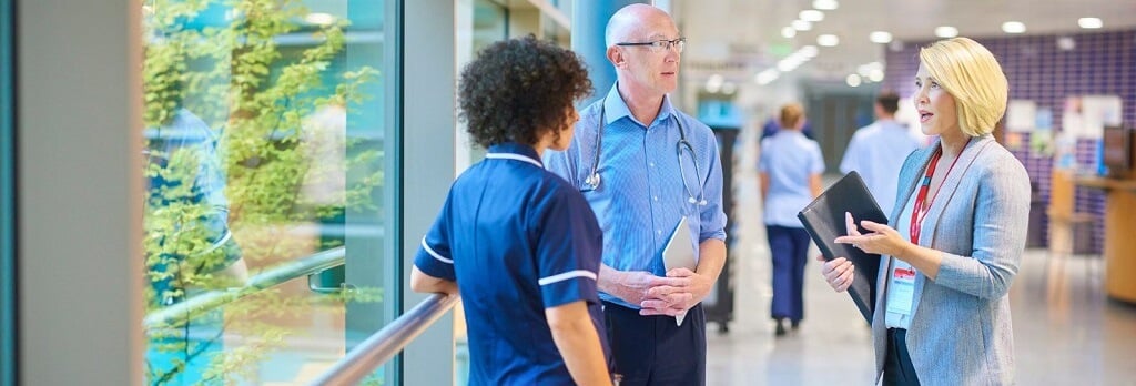 Three hospital workers talking in corridor
